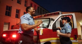 Two Emergency Medical Technicians eating McDonald's outside of an ambulance
