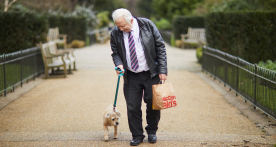 Man walking dog holding a bag of McDonald's